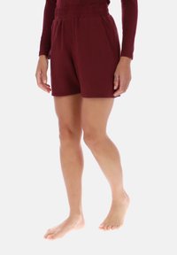 Bordeauxrode korte broek gemaakt van zachte stof, met een elastische tailleband en zijzakken. Ontworpen voor comfort met een rechte snit.