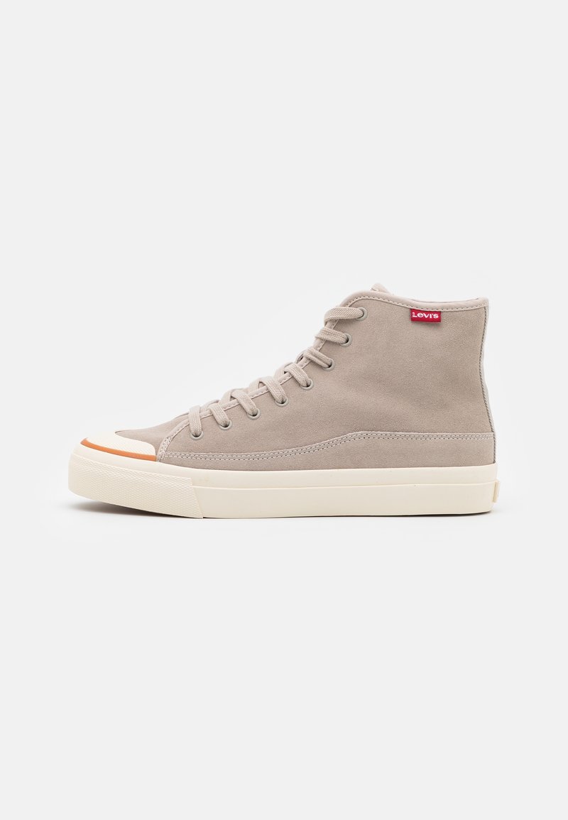 Baskets montantes en daim beige avec semelle en caoutchouc blanche, lacets beiges, détail d'embout orange et étiquette logo Levi's rouge près de la cheville.