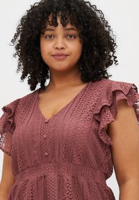 Lace dress in mauve with a V-neck, short ruffled sleeves, and button details, featuring intricate crochet patterns throughout.