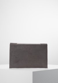 Grå mockaväska med rektangulär form, slät yta och minimalistisk design. Bakifrån visas rena sömmar och ingen ytterligare hårdvara.