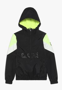 Černá větrovka s kapucí, s akcentními panely v neonově žluté a bílé barvě, předním zipem, elastickými manžetami a výrazným textovým motivem na přední straně.