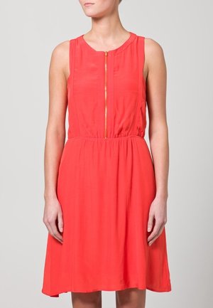 Robe sans manches rouge avec un décolleté rond, fermeture éclair dorée à l'avant, taille froncée et jupe évasée. Tissu lisse avec une texture légère.
