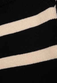 Schwarzer Strickstoff mit zwei großen horizontalen cremfarbenen Streifen. Die Textur ist gerippt, was den visuellen Kontrast zwischen den Farben verstärkt.