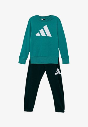 Sudadera de manga larga color azul verdoso con el logo blanco de Adidas, combinada con pantalones deportivos negros que llevan el mismo logo blanco de Adidas en la pierna.
