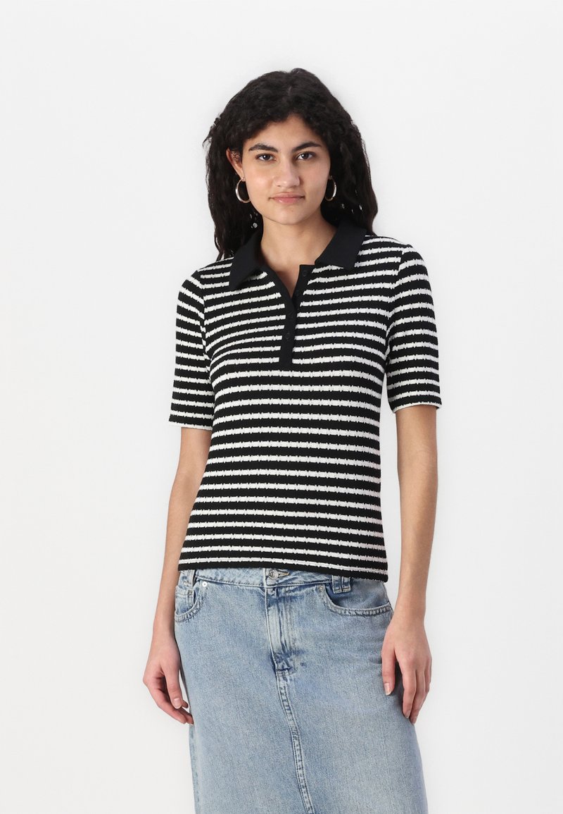 Svart og hvitstripet kortermet polo med en ensfarget svart krage. Ribbete tekstur, tettsittende design, brukt med et denimskjørt.