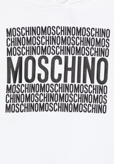 T-shirt bianca a maniche corte con logo "MOSCHINO" nero ripetuto in diverse dimensioni e orientamenti sulla parte anteriore. Tessuto morbido.