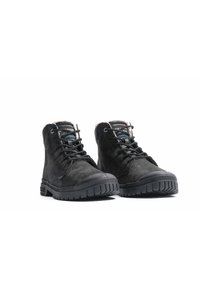 Svarta läderankleboots har en texturerad yta, rund tå, robusta snörningar och en slitstark, mönstrad gummisula med en liten klack.