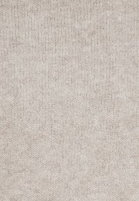 Light beige knitted fabric featuring a fine texture, with a consistent pattern of small, tight stitches across the surface.