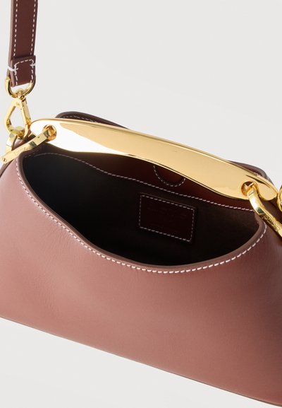 Μικρό μωβ δερμάτινο τσαντάκι με λευκές ραφές, αποσπώμενο καφέ λουράκι και λαμπερό χρυσό μεταλλικό χερούλι σε λευκό φόντο.