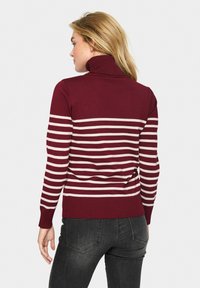 Pull maroon avec des rayures horizontales blanches, col haut, manches à bords côtelés et ourlet. Tissu doux, coupe ajustée et poids moyen.
