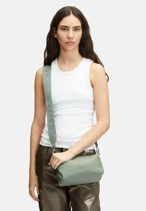 Sac en cuir vert à bandoulière avec fermeture éclair, logo embossé et sangle ajustable. Texture lisse, forme rectangulaire compacte.
