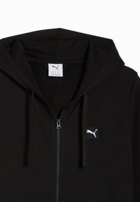 Sort zip-up hættetrøje lavet af blødt stof, med en frontlynlås, snørehætte og et lille hvidt Puma-logo på brystet.