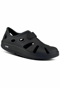 Black plastic clogs with ventilation holes and an adjustable strap. Rounded toe and a textured sole for grip. Lightweight design.