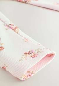 Helles rosa, geripptes Gewebe mit floralem Muster, das kleine Rosen in verschiedenen Farben zeigt. Abgerundeter Bündchenrand mit inneren Nähdetails.