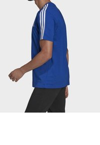 Kungablå atletisk t-shirt med vita tre-strängade detaljer på axlarna. Korta ärmar, rund hals, slim fit, slät tygstruktur.