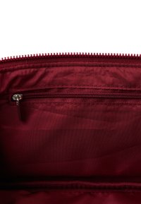 Burgundowa torba materiałowa z wnętrzem zawierającym kieszeń na zamek błyskawiczny. Gładka tekstura, wykończenie podszewki oraz kontrastowy zamek dla bezpiecznego zamknięcia.