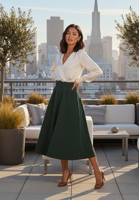 Biała satynowa bluzka z głębokim dekoltem w serek, zestawiona z zieloną spódnicą A-line z szerokim paskiem. Brązowe szpilki dopełniają stylizację.