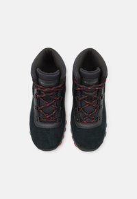 Czarne zamszowe buty do wędrówek z czerwonymi sznurowadłami, wyściełanym kołnierzem i gumową podeszwą. Posiadają logo na języku oraz wiele oczek do sznurowania dla zapewnienia pewnego dopasowania.