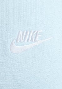 Tessuto azzurro chiaro con un logo Nike bianco ricamato, dalla texture liscia. Il design è minimalista, senza ulteriori motivi o accenti.