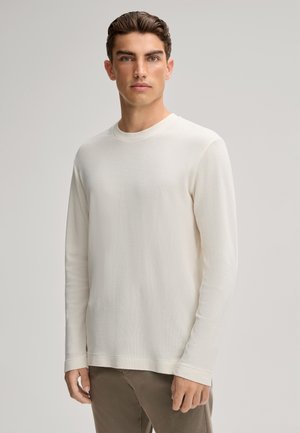 Helles Creme langärmliges Shirt mit Rundhalsausschnitt und strukturiertem Strick. Glattes Material, lockere Passform und dezente Nahtdetails.