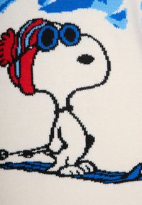 Maglione a maglia con Snoopy che indossa occhiali da sole blu, una sciarpa rossa e un contorno nero su uno sfondo bianco, con accenti blu in basso.