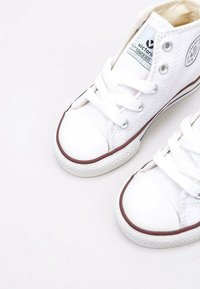 Witte canvas hoge sneakers met rubberen neuzen, contrasterende bruine accenten langs de zolen en witte veters. Voorzien van logo patch op de tong.