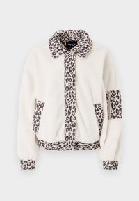 Uska jakna od umjetnog krzna u krem boji s krznom od leoparda na ovratniku i detaljima. Ima dva prednja džepa i elastične rukave za prilagođen izgled.