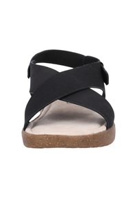 Svart sandal med korsade remmar, en vadderad sula och en texturerad korksula. Minimalistisk design, lämplig för avslappnad användning.