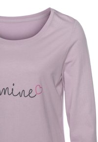 Hellblaues Langarmshirt mit weitem Ausschnitt, das das Wort "mine" in schwarzer Schrift und einem kleinen rosa Herzakzent zeigt. Weiche Stofftextur.