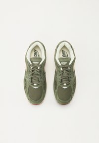 Chaussures de sport en maille verte avec semelles en caoutchouc, dotées d'un col rembourré et d'un design à lacets. Accents blancs et roses notables sur les côtés.