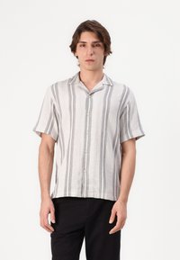 Camisa de botones de manga corta en una tela ligera, con un patrón a rayas en gris y blanco. Cuello clásico y diseño de corte holgado.