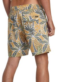 Costumi da bagno da uomo gialli con motivo tropicale di foglie verdi e bianche. Presentano una vita elasticizzata e una tasca laterale con chiusura a scatto.