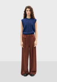 Top senza maniche blu in maglia e pantaloni larghi marroni. Il top presenta un motivo testurizzato; i pantaloni hanno una tasca laterale e una vestibilità comoda.