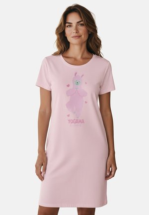 Woman wearing a light pink knee-length dress with a cartoon pink llama and "YOGAMA Llama" text on front against a plain background.