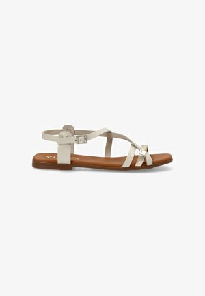 Sandal plano con suela marrón, correas sintéticas blancas y cierre de hebilla. Presenta un diseño minimalista con una plantilla texturizada.