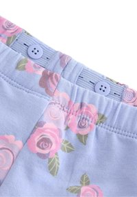 Ljusblått tyg med ett blomstertryck som visar rosa rosor. Midjan har en lila knapp och ett elastiskt band för justerbar passform.