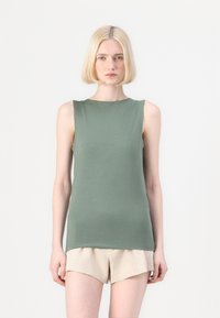 Uten ermer grønn bomullstopp med rund hals, figurnær design og glatt tekstur, sammen med lysbeige shorts.