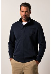 Giacca con zip blu navy in misto cotone, con tasca frontale e logo in rilievo. Polsini e vita a coste, texture liscia.