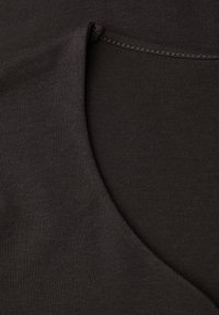 Černá tkanina s hladkým povrchem; má zakřivený šev a okraj výstřihu s pečlivým stehem. Minimální design bez viditelných vzorů.