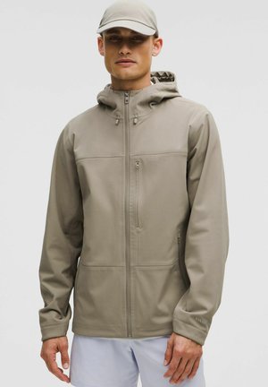 Lichtbeige hoodie met een soepele, flexibele textuur. Voorzien van een rits, twee voorzakken en verstelbare trekkoorden voor de capuchon.