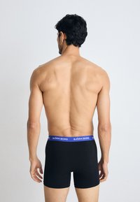 Fekete boxerpants, rugalmas szövetből, kék derékkal, rajta a "BJÖRN BORG" felirattal. A dizájn egyszerű és testhezálló.