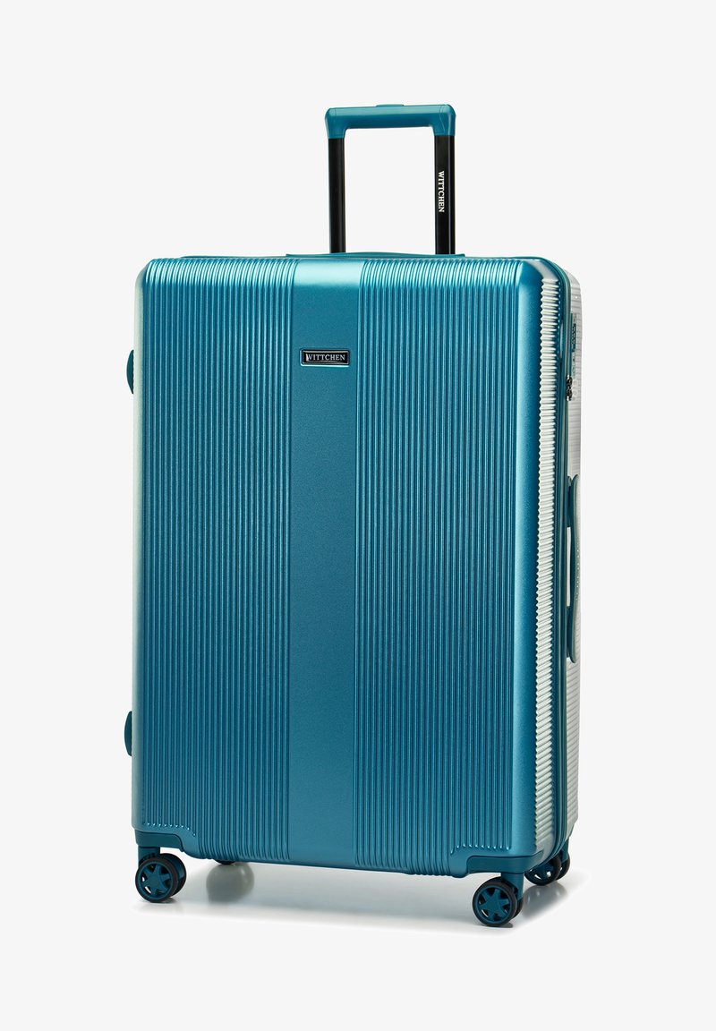 Valise rigide en teal, avec des nervures verticales, une poignée rétractable, quatre roues, et un logo sur le devant. Fini lisse.