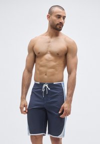 Pantaloni scurți de înot bleumarin cu panouri laterale albastre deschis, talie cu șnur și cusături albe. Confecționați din material neted, care se usucă rapid.