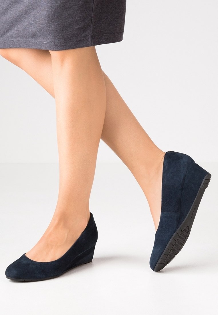 Scarpe con zeppa in suede blu navy, con punta arrotondata e superficie texturizzata. La suola è nera con una presa decorata per migliorare la trazione.