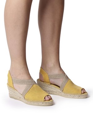 Żółte sandały na koturnie espadryle z odkrytymi palcami, elastycznymi paskami, plecioną podeszwą z juty oraz kontrastującymi beżowymi akcentami.