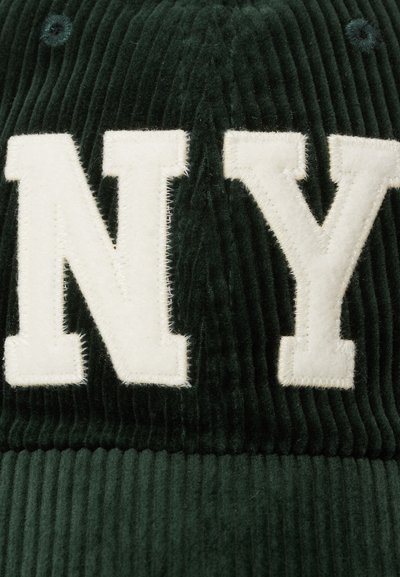 Boné de corduroy verde escuro com bordado branco "NY". Tecido texturizado com ripas, forma estruturada e detalhes de costura visíveis.