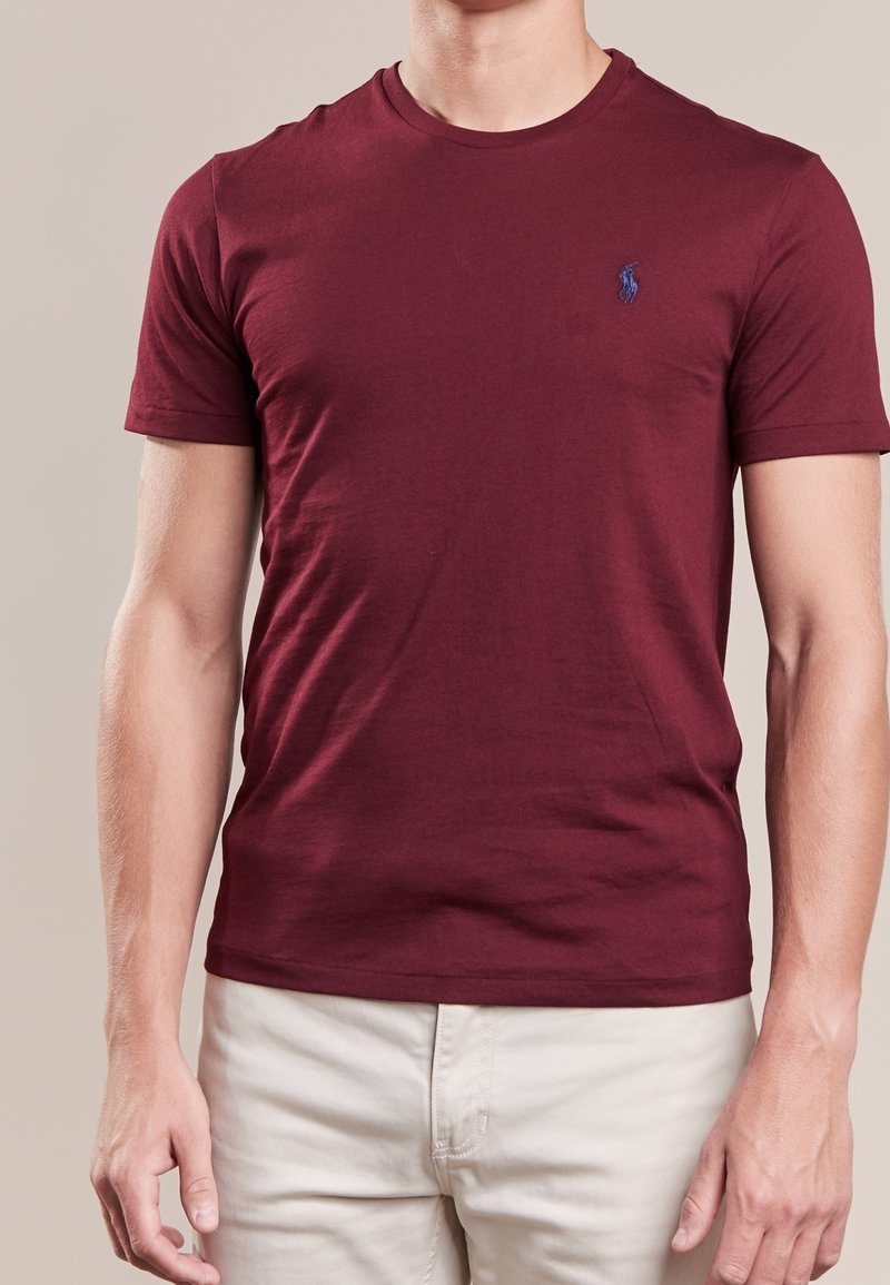 Marošové tričko s krátkým rukávem vyrobené z měkké tkaniny; má malé modré logo na levé hrudi. Design s kulatým výstřihem a běžným střihem.