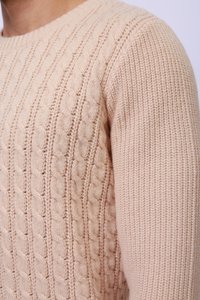 Pull en tricot câble rose clair avec un col rond côtelé et des motifs texturés, présentant une coupe ajustée et une texture douce et moelleuse.