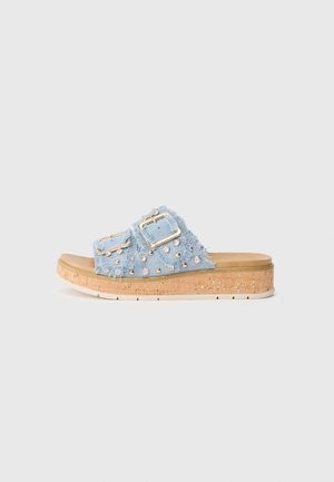 Sandale slide en denim bleu clair avec deux brides à boucles ornées de clous et de strass, semelle plateforme en liège et semelle extérieure en caoutchouc blanc.