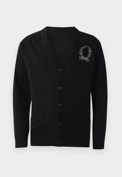 Melnā kardigāna ar V-veida kakla izgriezumu, pogu aizdari, ribinātām aprocēm un apakšmalu, divām priekšējām kabatām un izšūtu ziedu vainagu uz kreisās krūtis.